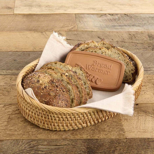 Bread in a woven basket with a bread warmer on a wooden surface