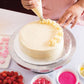 Person decorating a cake with white frosting on a white surface.