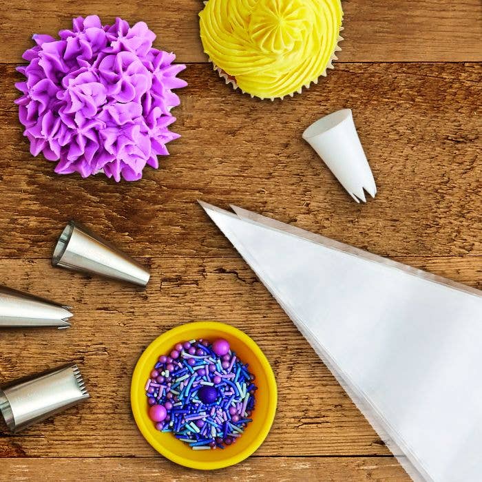 Baking tools including a piping bag, frosting tips, and sprinkles on a wooden surface.