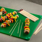 Colorful vegetable skewers on a green cutting board with wooden skewers and a package.