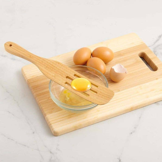 Wooden egg separator on a cutting board with eggs and a bowl of separated yolk.
