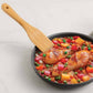 Frying pan with chicken and vegetable stir-fry on a marble surface
