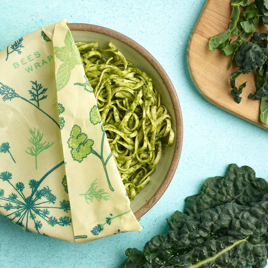 Beeswax wrap with a green leaf pattern on a blue background, used to wrap green pasta.