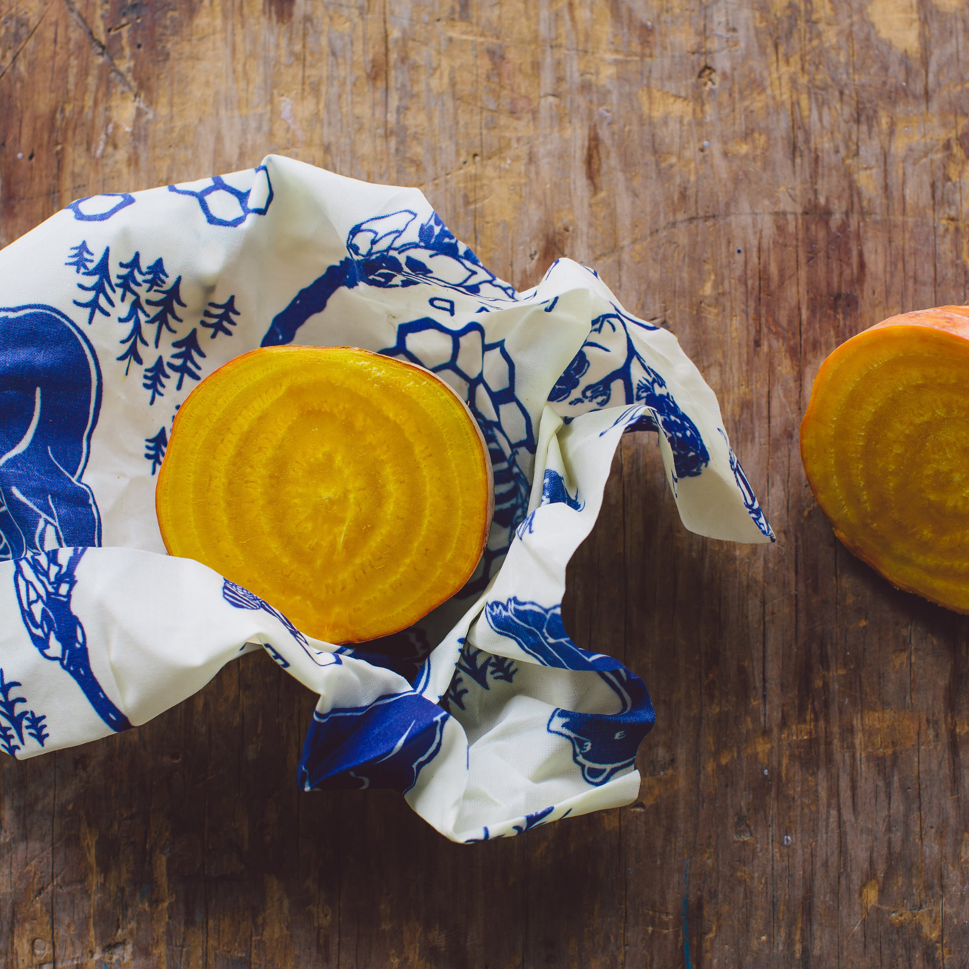 Yellow bar of soap wrapped in a blue and white patterned cloth on a wooden surface.