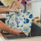 Person holding a reusable fabric bag over a sink with water running through it.