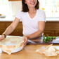 Woman in a kitchen using beeswax food wrap on a wooden cutting board.