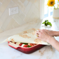 Person using silicone food wrap on a dish with vegetables in a kitchen setting