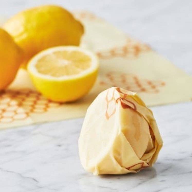 Lemons and a crumpled piece of paper on a marble surface with a tortilla in the background.