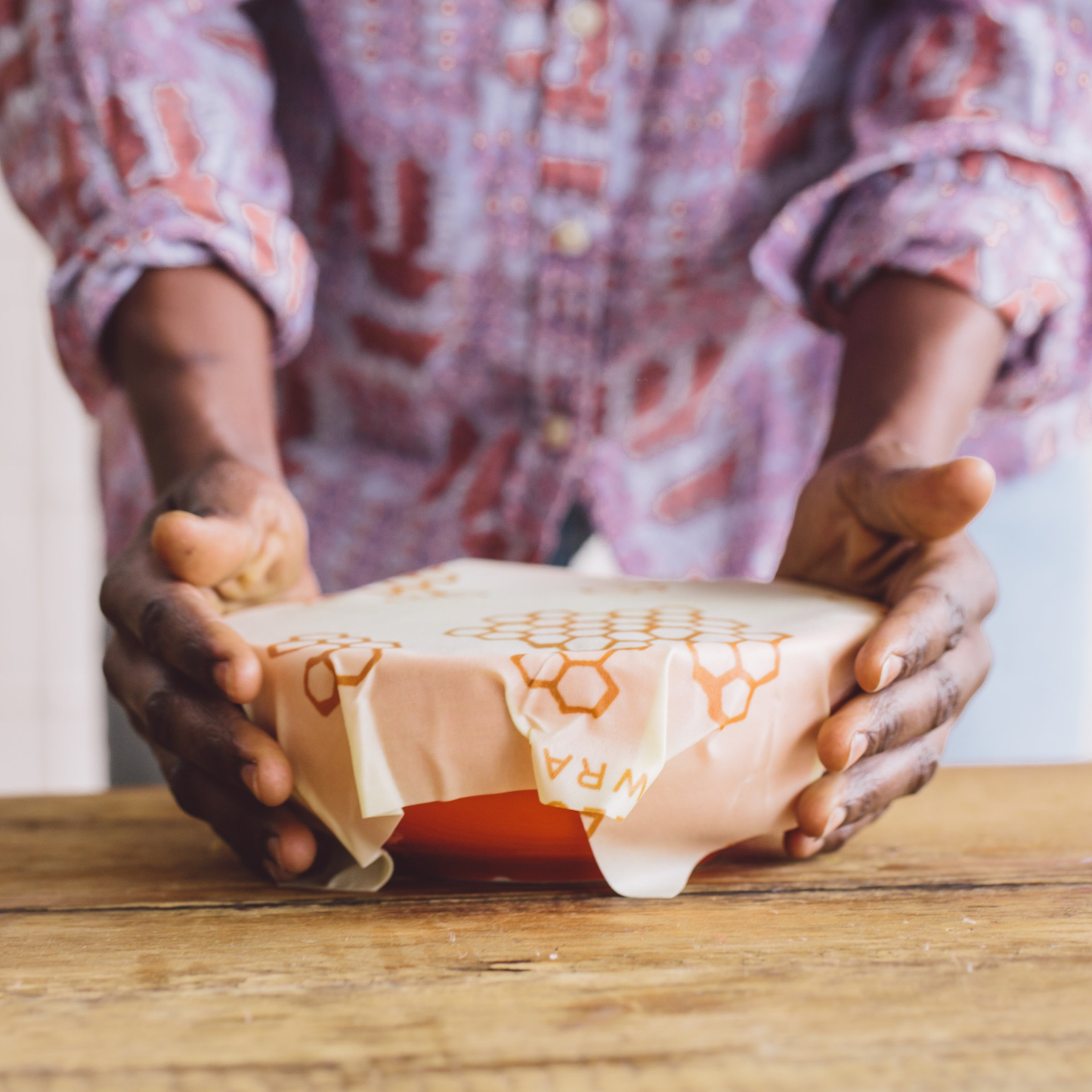 Person holding a wrapped product on a wooden surface