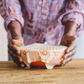 Person holding a wrapped product on a wooden surface