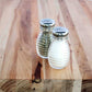 Two glass salt and pepper shakers on a wooden surface