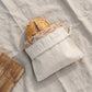 Loaf of bread in a white drawstring bag on a textured surface