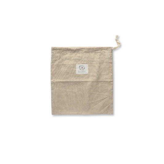 A light beige cotton drawstring pouch with a small white square label on the front, shown against a plain white background.
