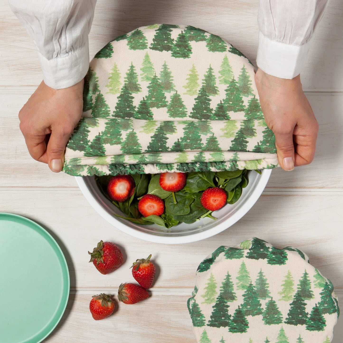 Reusable food wraps with tree pattern being used to cover a bowl of salad on a wooden surface.