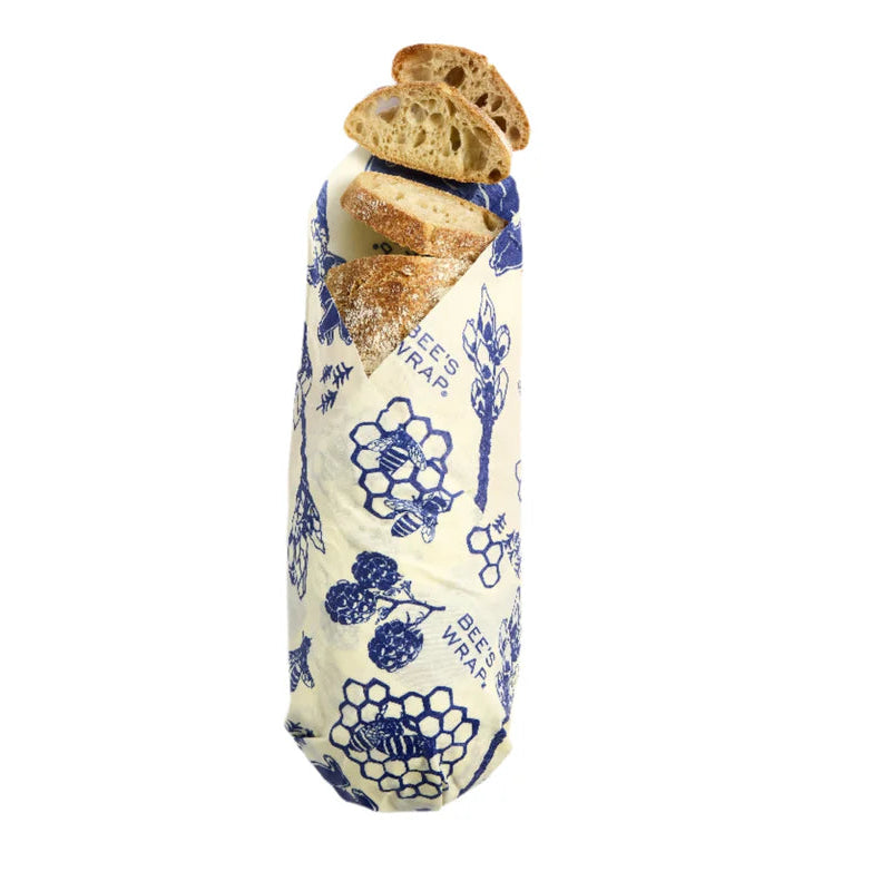 Baguette wrapped in a blue and white patterned bees wrap on a white background