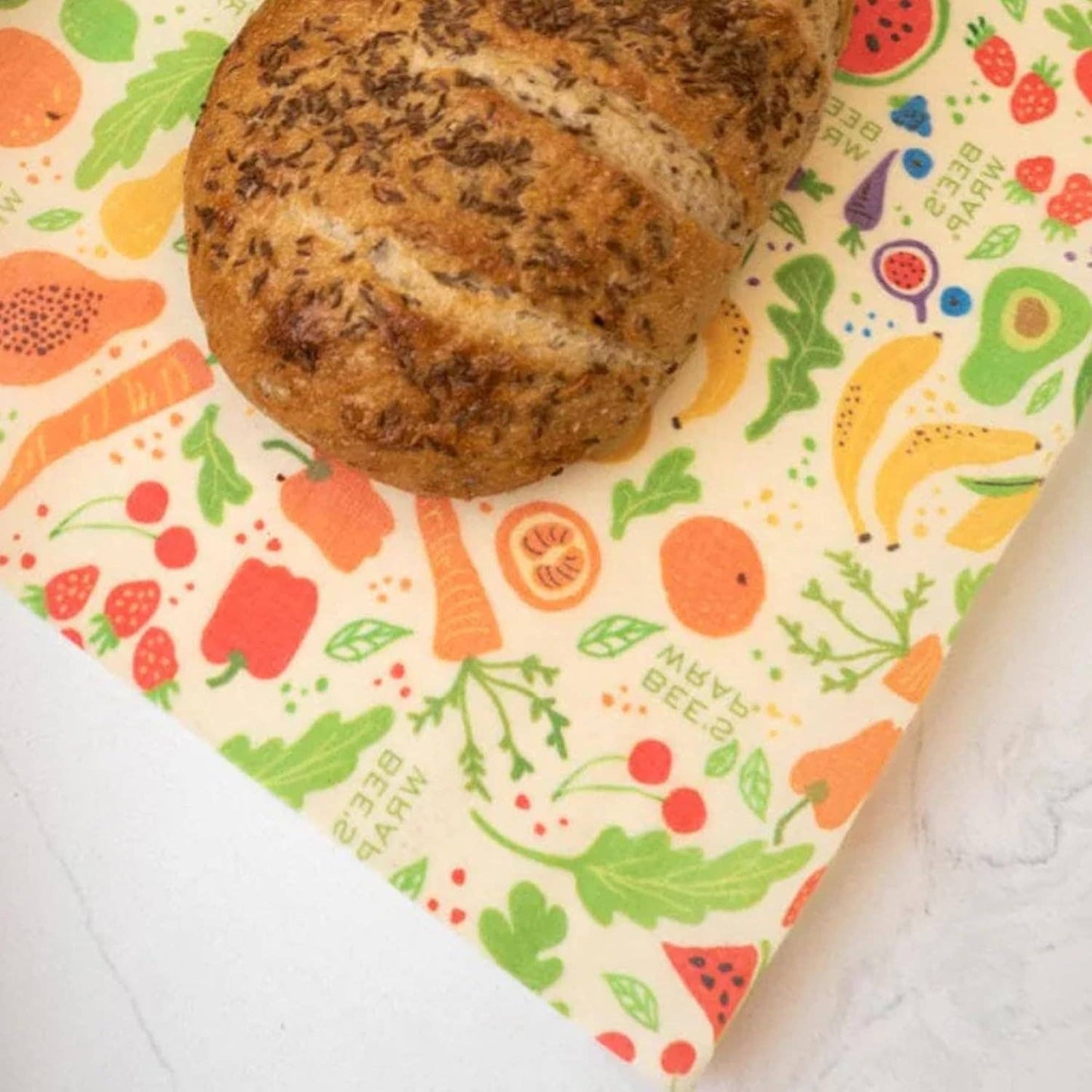Loaf of bread on a colorful reusable shopping bag with fruit and vegetable pattern