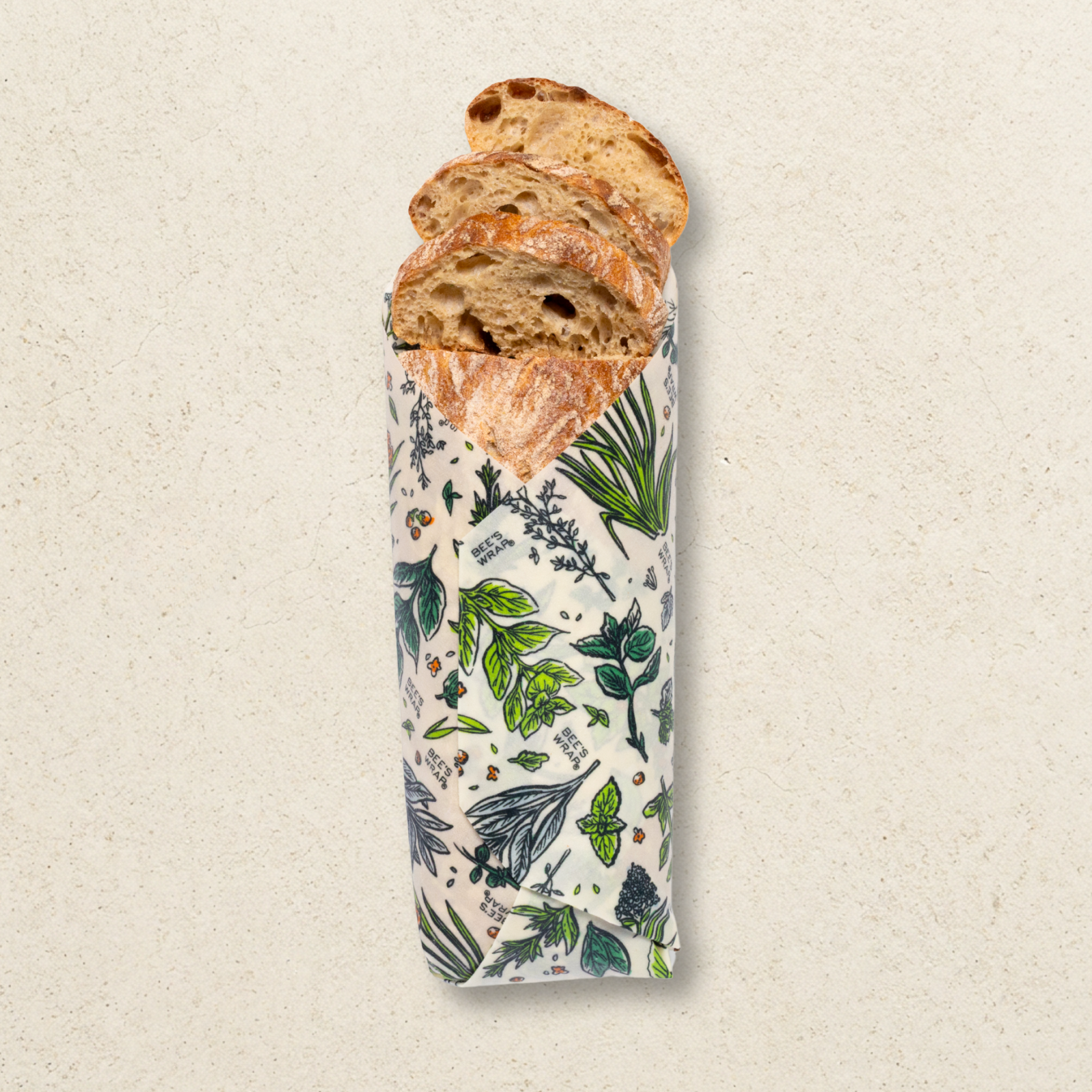 Loaf of bread wrapped in a botanical patterned paper on a beige background