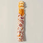 Baguette wrapped in a patterned paper on a light gray background