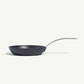 A black carbon steel frying pan with a stainless steel handle, pre-seasoned and ready for cooking on a white background.