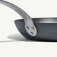 A black carbon steel frying pan with a stainless steel handle, pre-seasoned and ready for cooking on a white background.