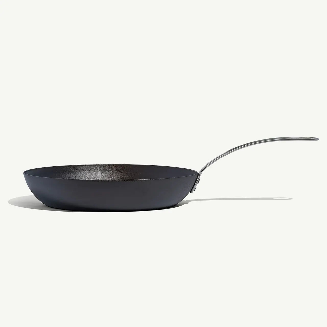 A black carbon steel frying pan with a stainless steel handle, pre-seasoned and ready for use on white background.