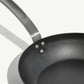 An 8-inch carbon steel frying pan with a gray surface and a stainless steel handle, pre-seasoned and ready for use on a white background.