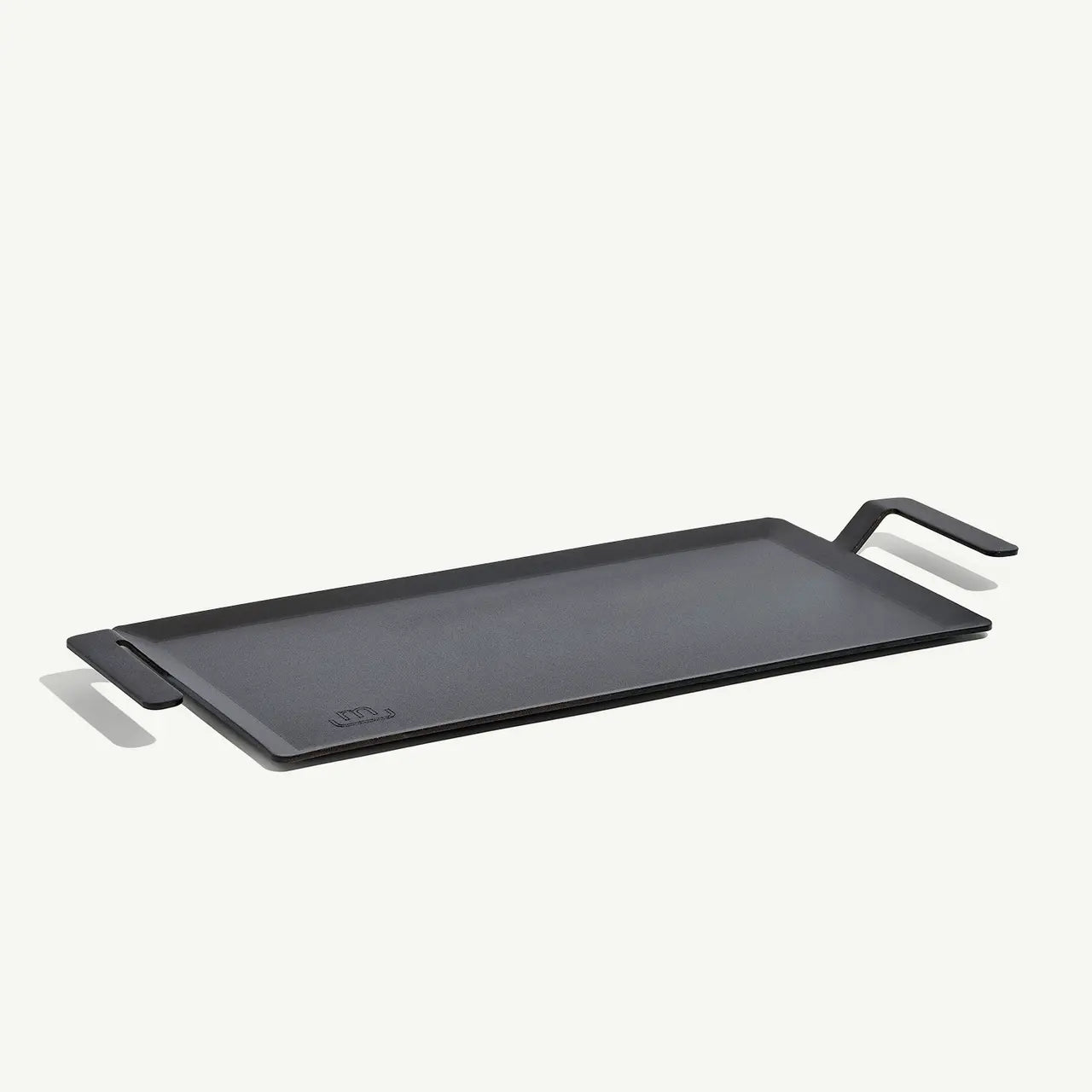 A black carbon steel griddle with raised handles, designed for use on stovetops and grills.