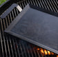 Black rectangular griddle on a grill outside. 