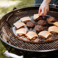 Person grilling burgers with cheese on a barbecue grill outdoors.
