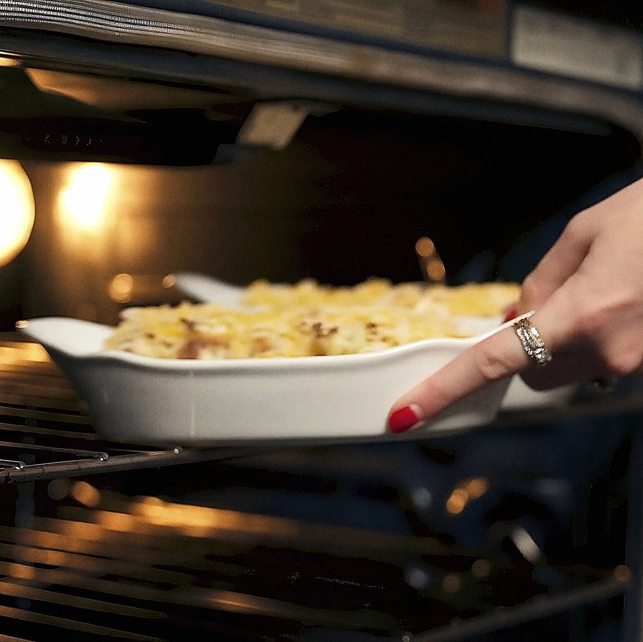Person reaching into an oven to take out a dish of food