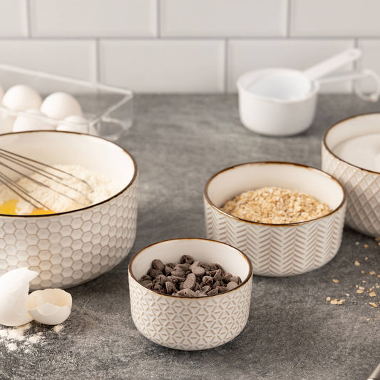 Set of ceramic bowls with kitchen items on a countertop