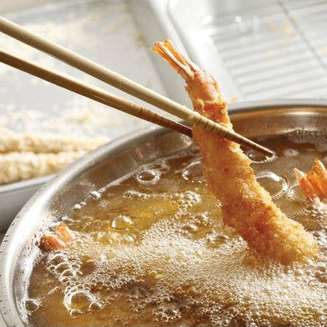 Shrimp tempura being fried in a pot with chopsticks