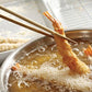 Shrimp tempura being fried in a pot with chopsticks