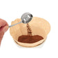Wooden coffee filter with ground coffee and a metal scoop on a white background