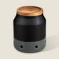 Black ceramic garlic keeper with a wooden lid on a beige background