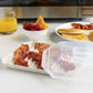 Breakfast setup with bacon, eggs, and pancakes on a kitchen counter.