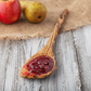 olive wood spoon with pointed end on a table with jelly and fruit