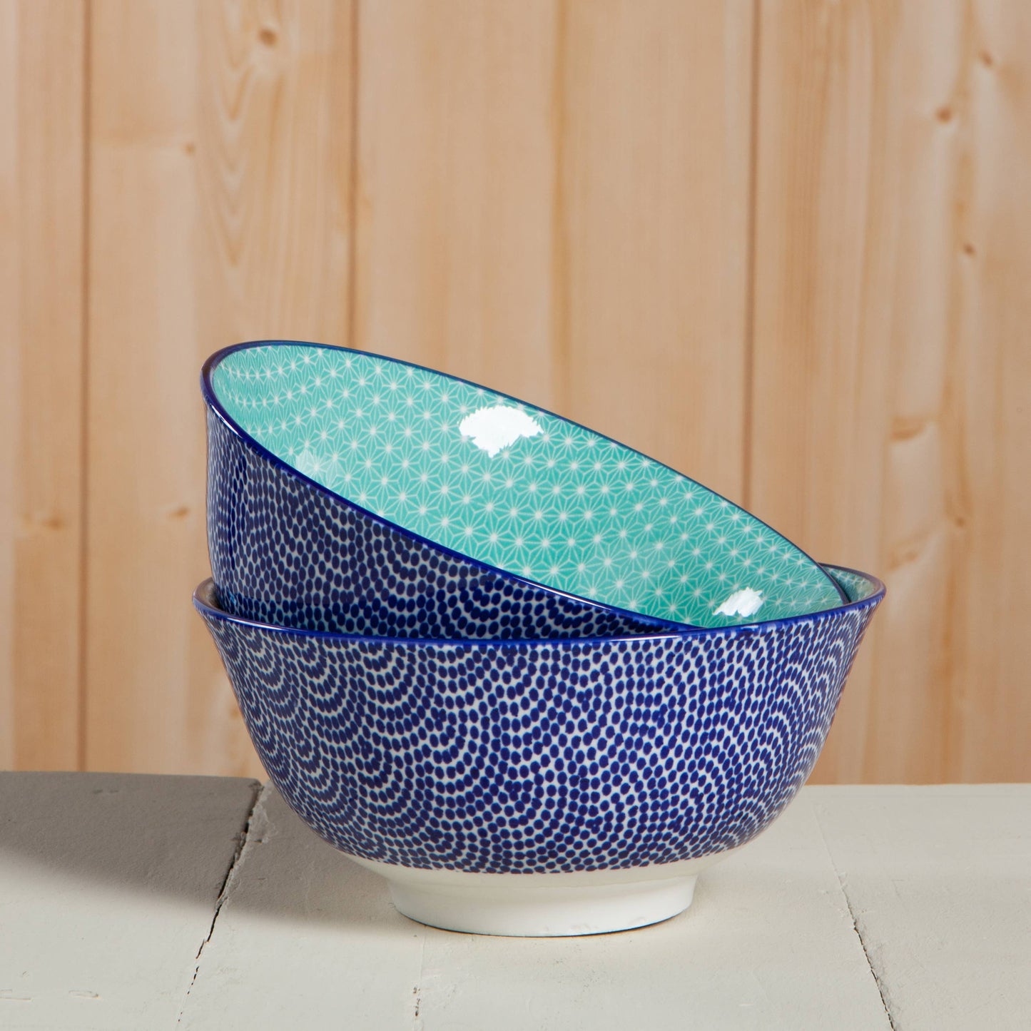 Two ceramic bowls with blue and green patterns on a wooden surface.