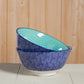Two ceramic bowls with blue and green patterns on a wooden surface.