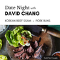 Promotional graphic for a food product featuring sliced beef ssam and pork buns on a wooden board with lettuce wraps, alongside a large knife, on a dark textured background. Text at the top reads 'Date Night with DAVID CHANG' and 'KOREAN BEEF SSAM + PORK BUNS'.