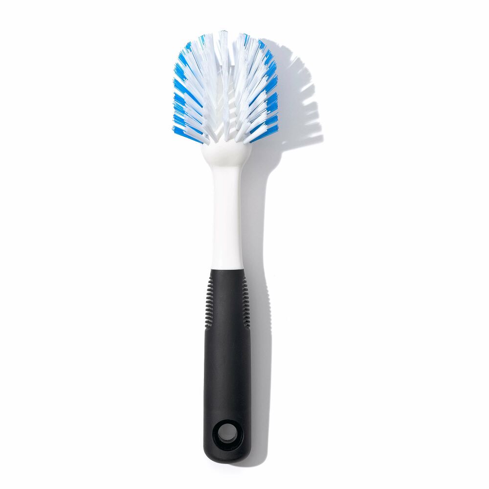 Dish brush with blue and white brissels and black handle on white surface. 