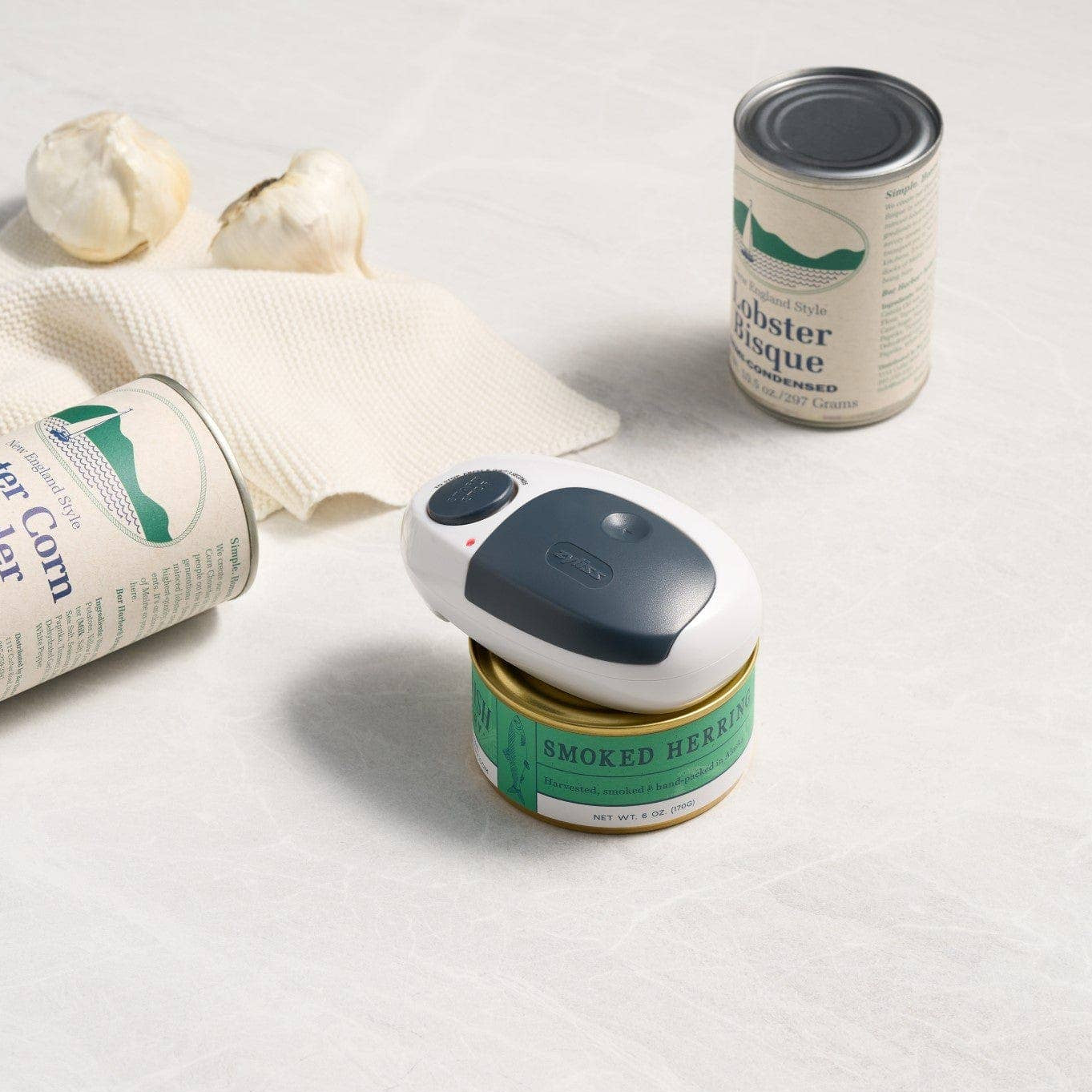 Three cans and a can opener on a light gray background