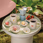 Round table with coffee cups, bowls, and strawberries outdoors