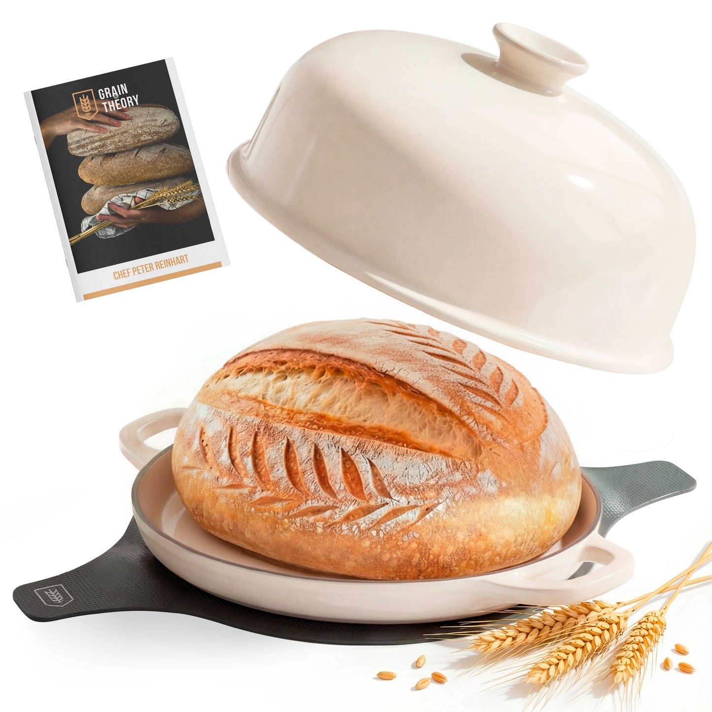 Loaf of bread in a ceramic dish with a lid, surrounded by wheat stalks on a white background.