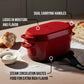 Red enameled cast iron roaster with features highlighted on a wooden surface with bread and flour.