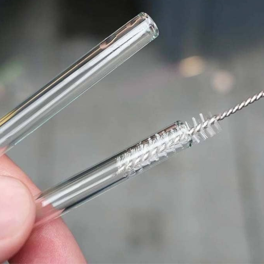 Hand using small thin brush to clean a clear straw on a gray background