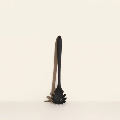 Black pasta server on a beige background