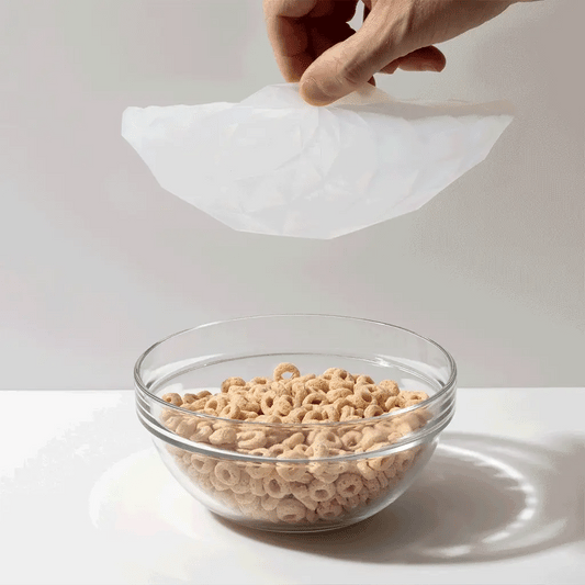 Gif of silicone lid being placed on a bowl of cereal on a white background