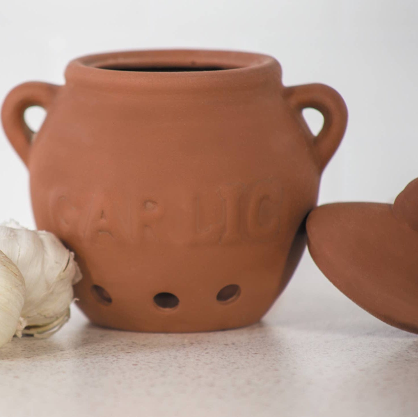 Keep your garlic fresh, organized, and protected with this elegant terra cotta garlic keeper. Made from porous, unglazed stoneware with vent holes, it promotes proper airflow to keep garlic cool, dry, and long-lasting.