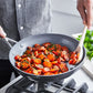 Person cooking carrots in a frying pan on a stove